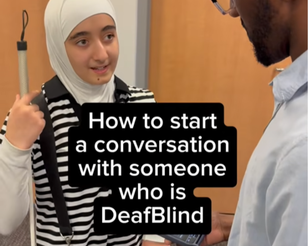 Young woman holding a white cane speaks with a man. Text reads: How to start a conversation with someone who is DeafBlind