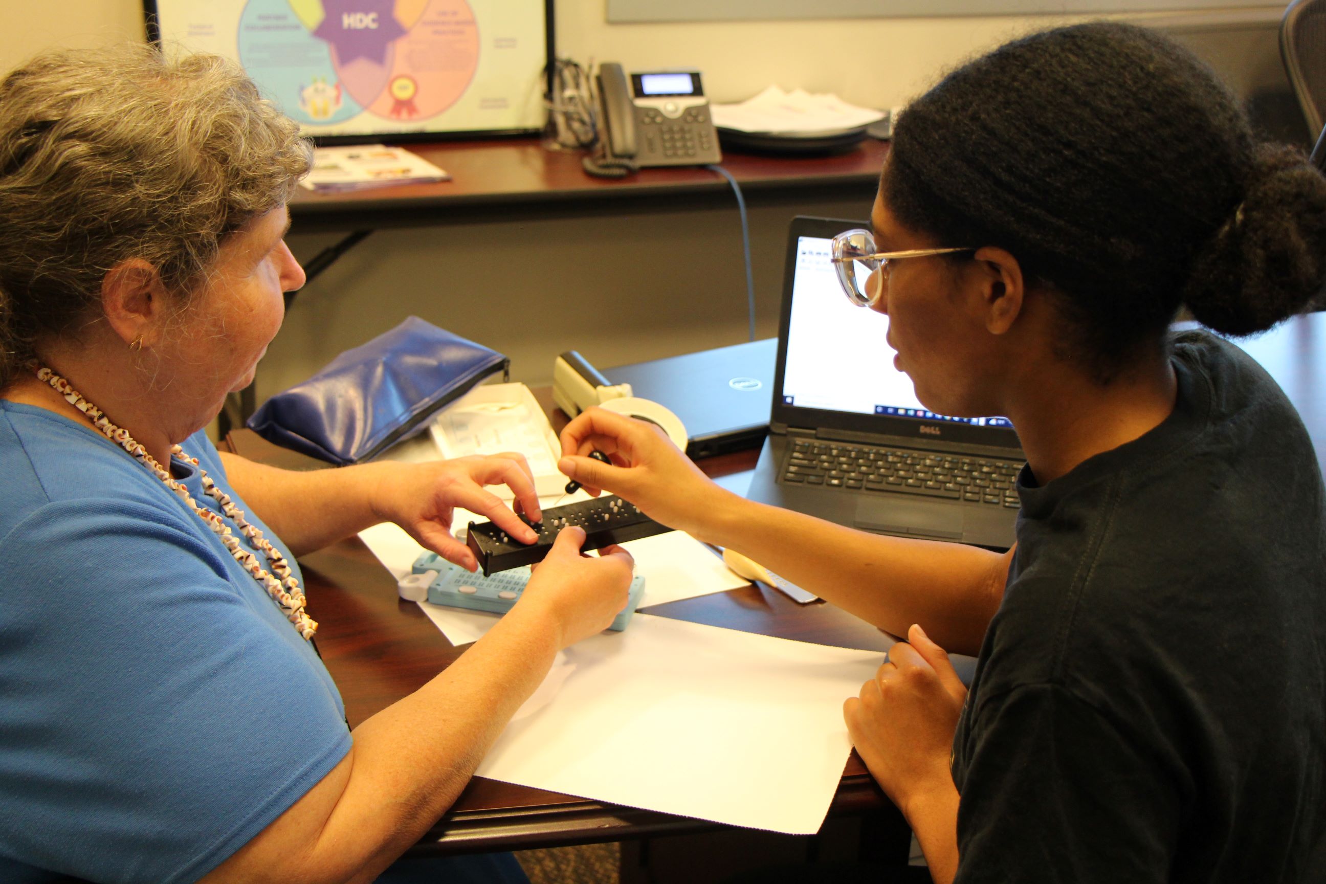 Student uses stylus and slate to create braille. 