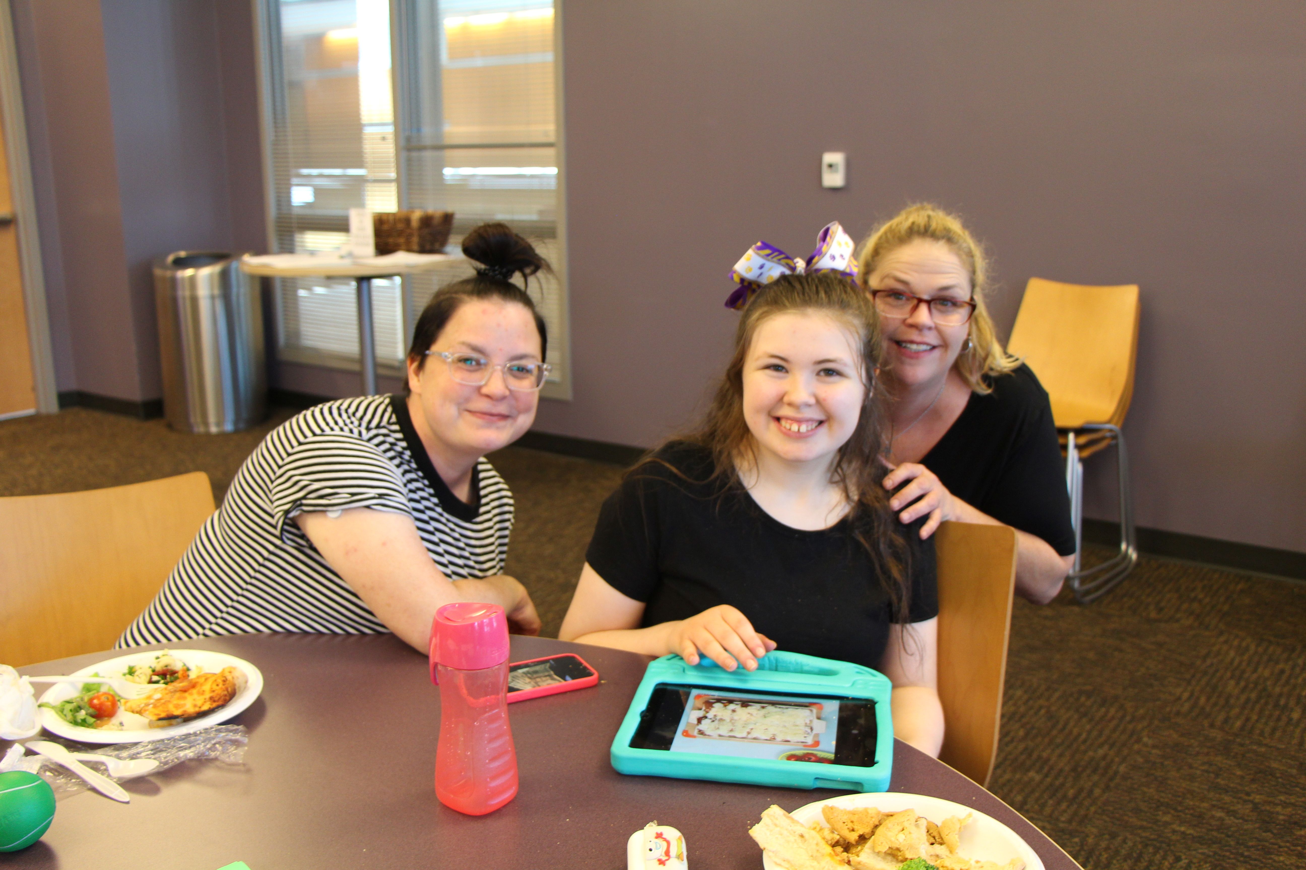 Jes Bates sits next to a girl and her mother.