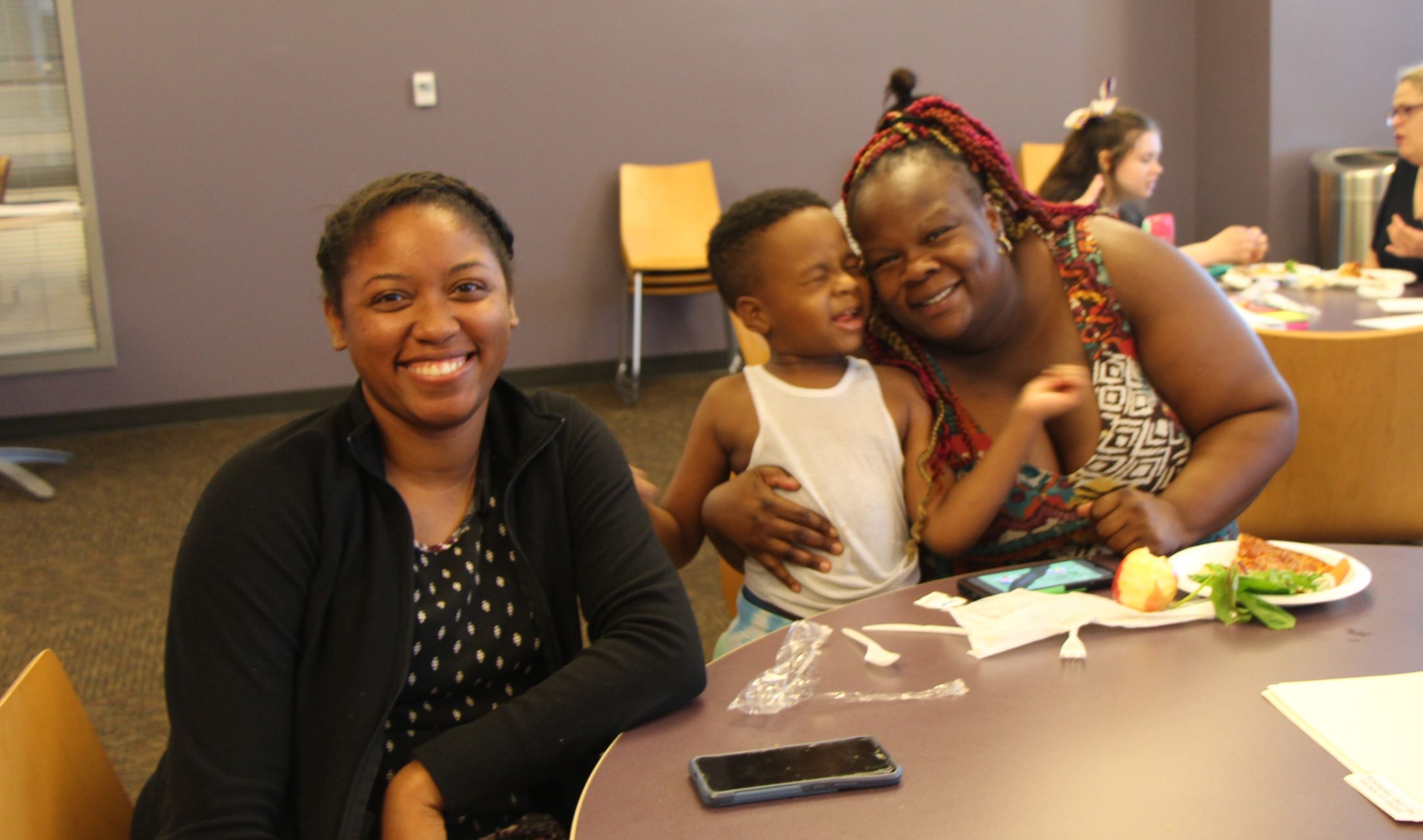 LEND scholar sits at table with mother and toddler. 