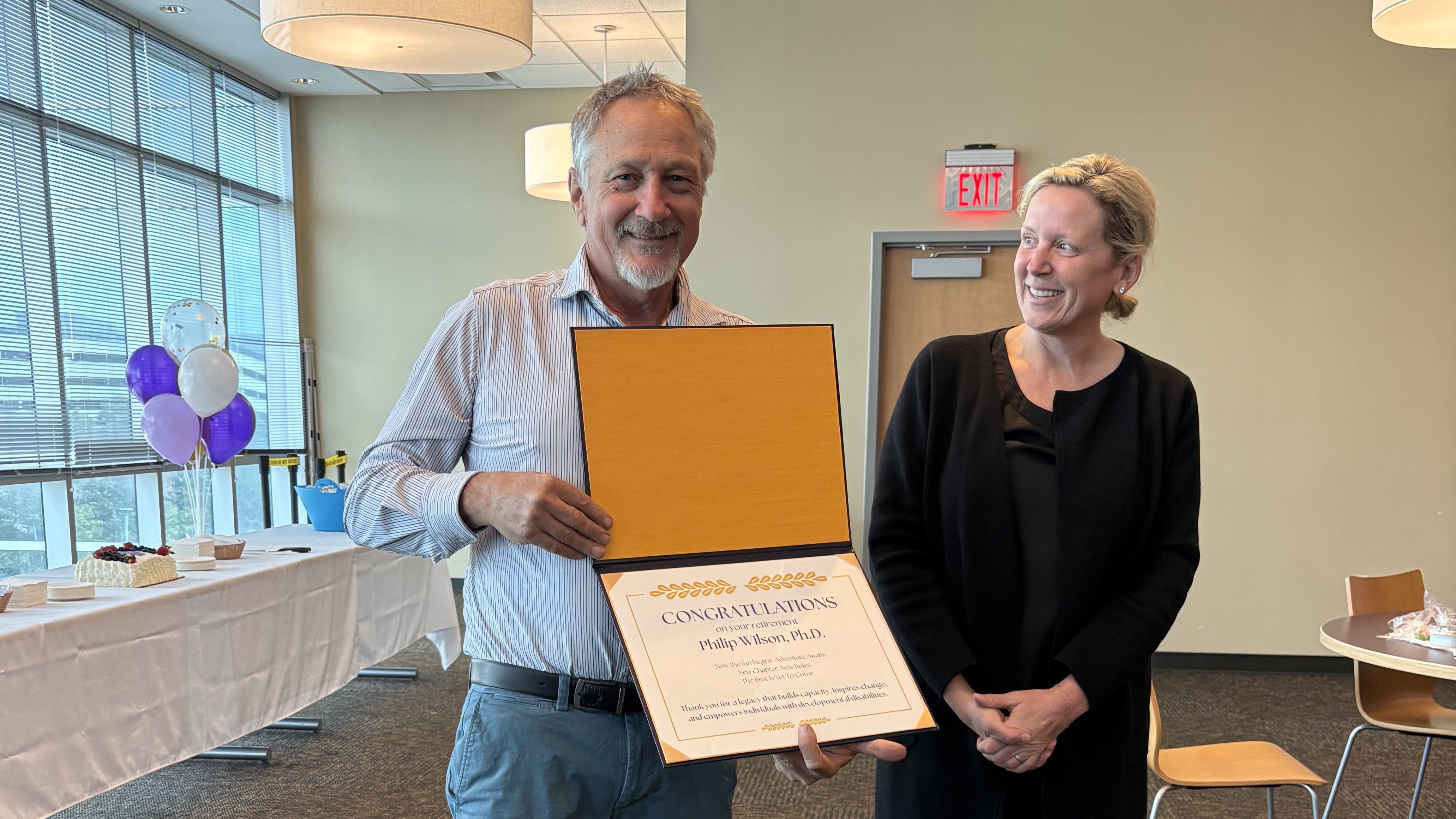 Dr. Wilson holding congratulatory retirement certficiate while Dean Dugan smiles warmly at him.