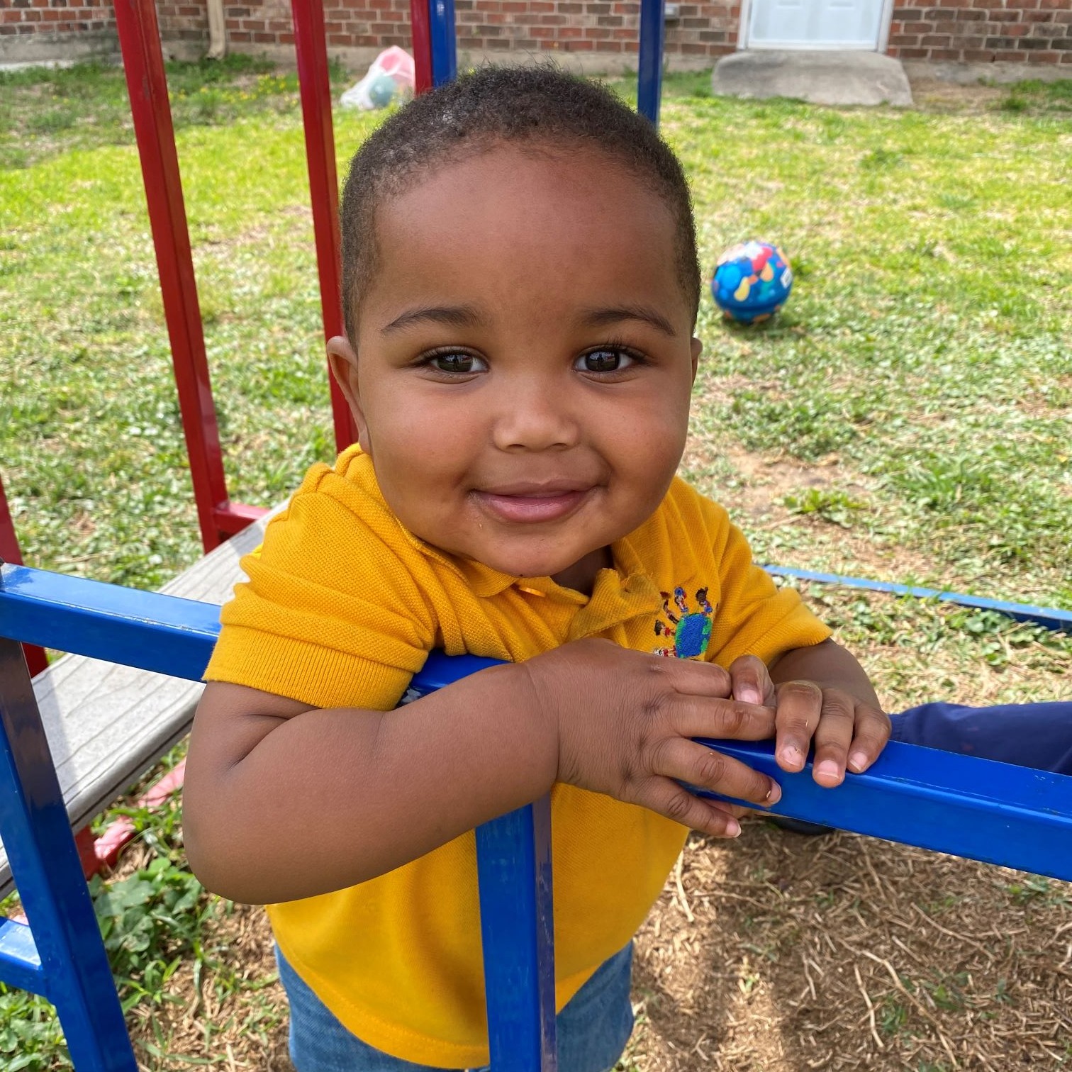 Boy wearing shcool uniform smiles on playground.