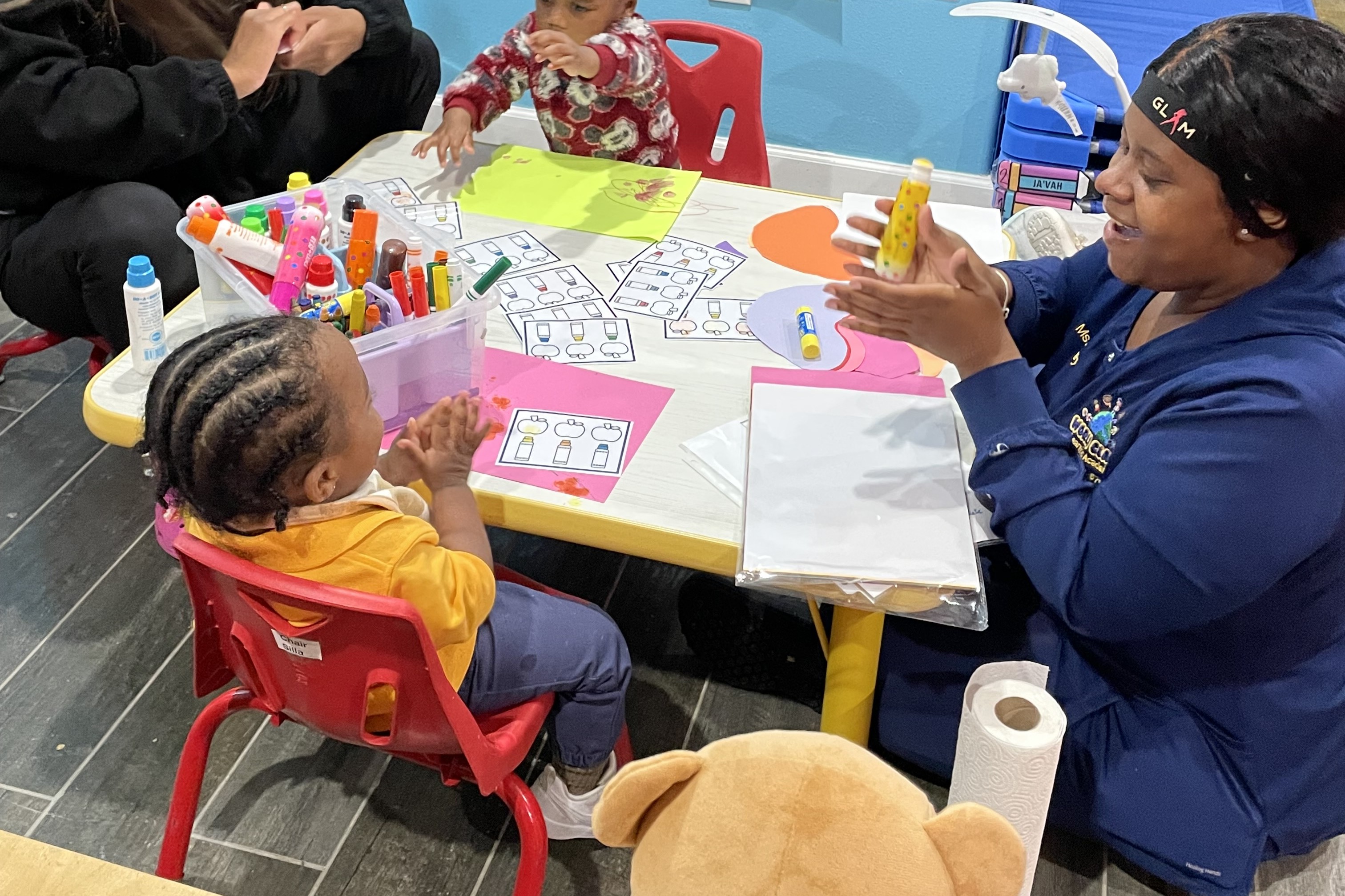 Teacher helps toddler paint.