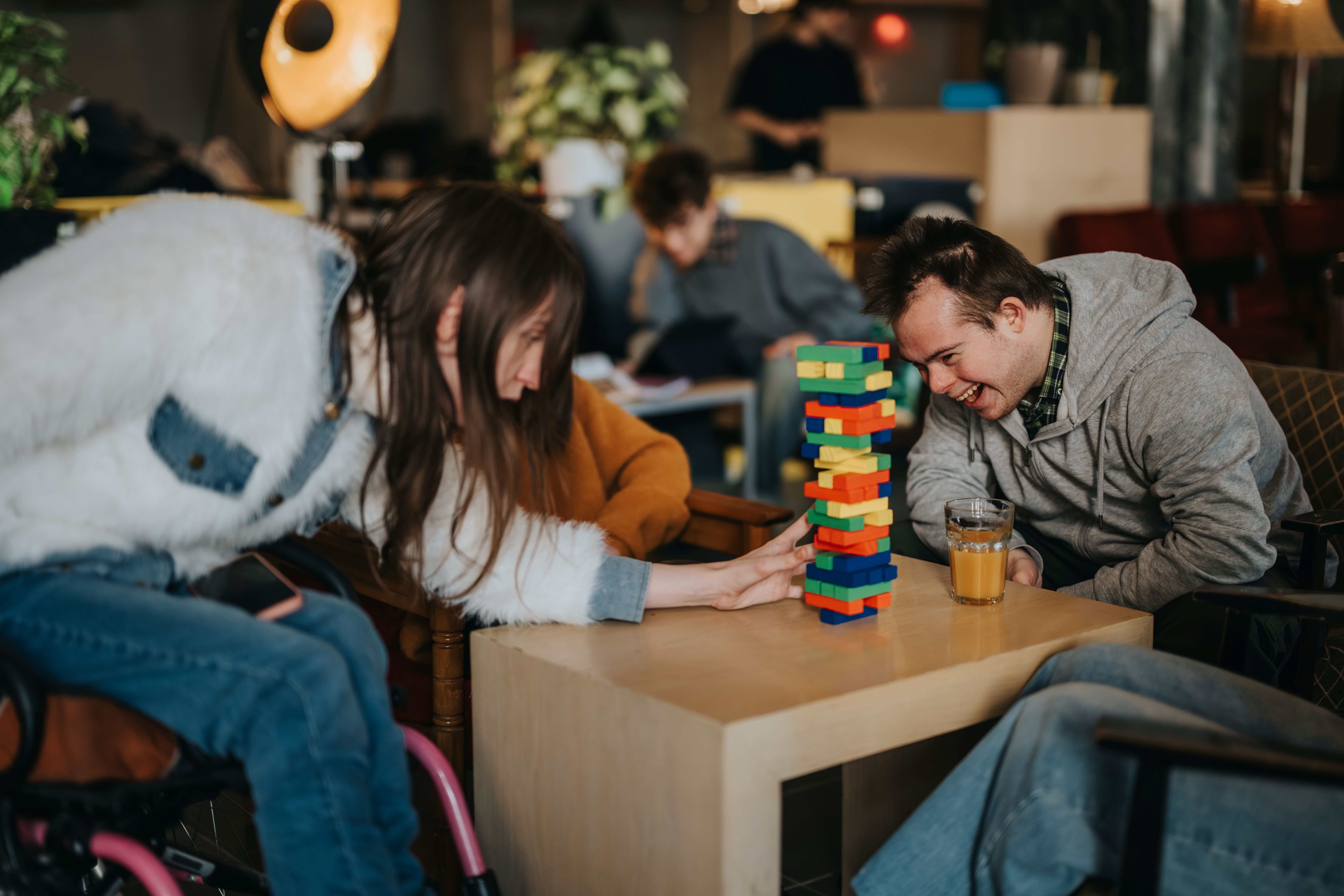 A man with Down syndrome and a woman in a wheelchair playing Jenga at a cafe