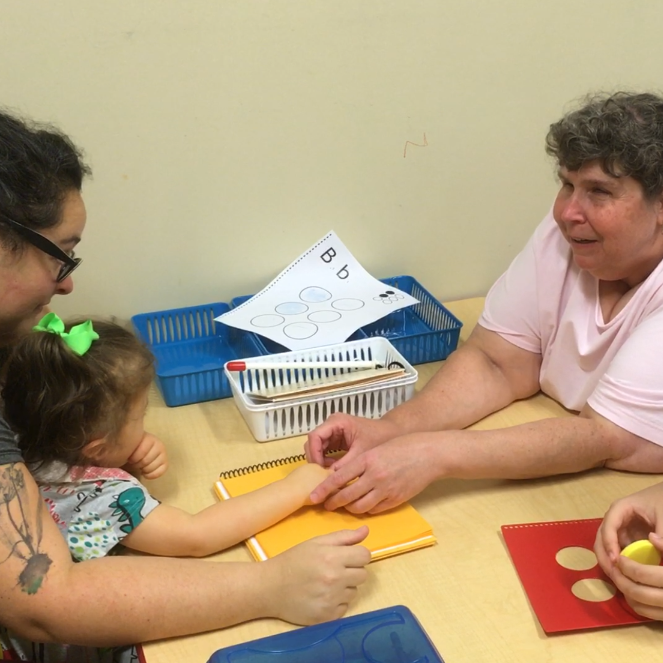 DeafBlind Intervener guides a young girl's hand over braille.