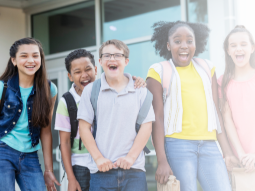 middle school students including a student with Down syndrome smile outside of school building.