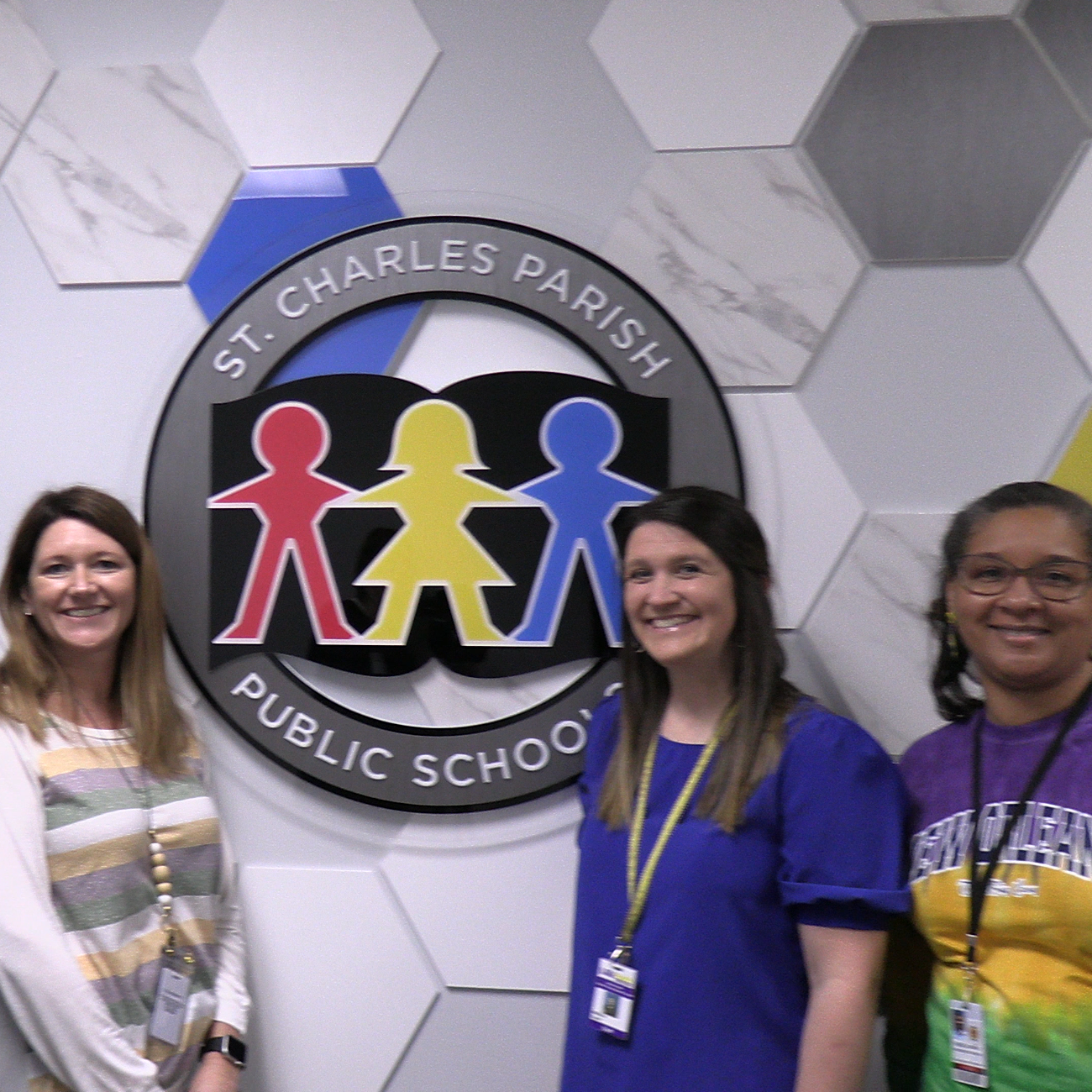 LASARD facilitator takes photo with S. Charles District partners in front of the St. Charles Public Schools logo.