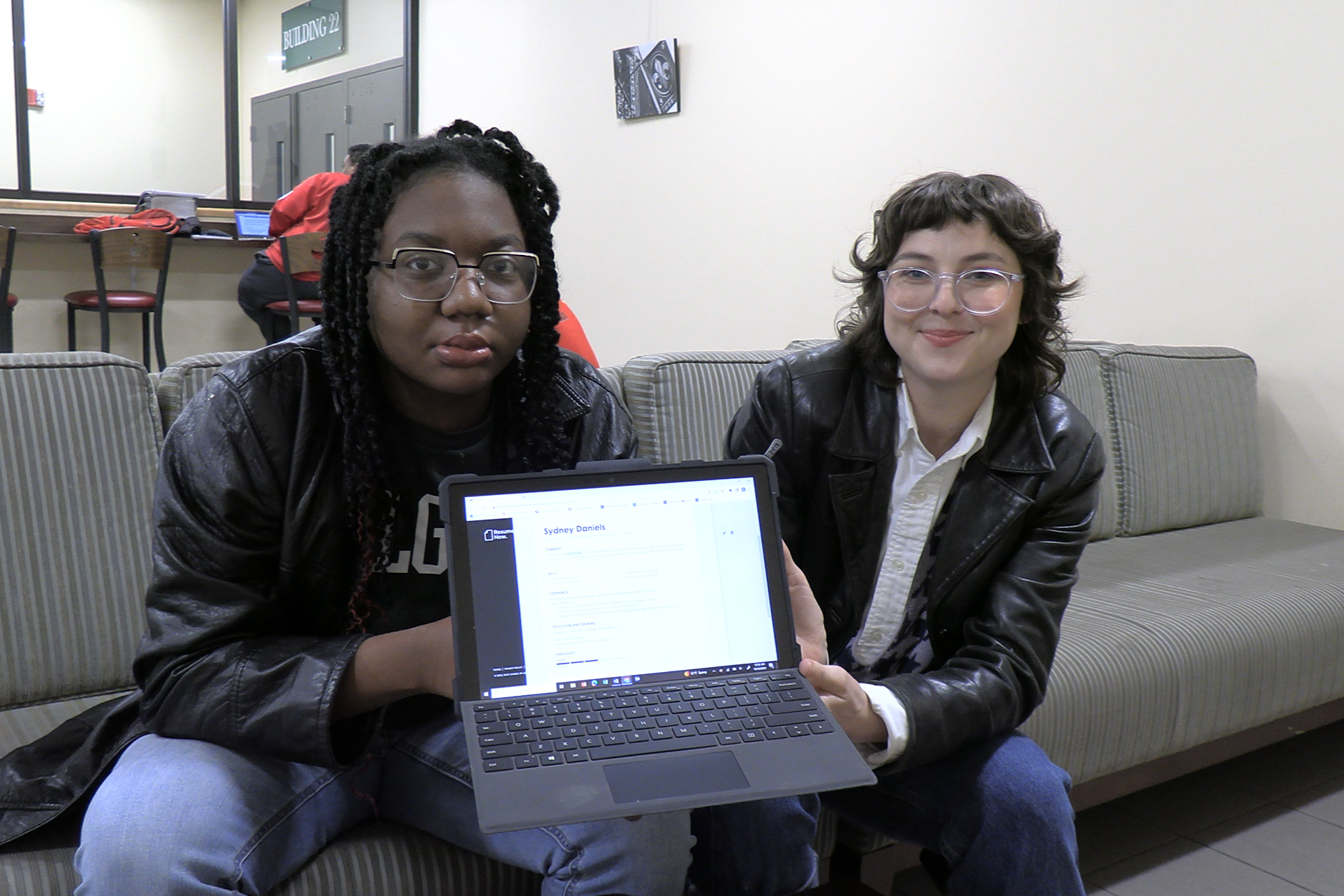 PAYCheck student holds up her resume on her laptop with her transition specialist.